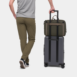 NOMATIC Laptop Bag in olive, worn on the back next to rolling suitcase, rear view