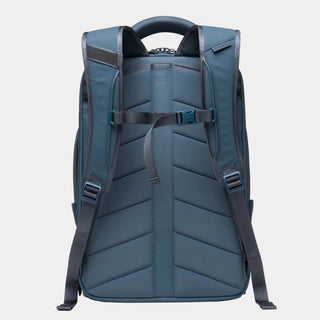 A dark slate blue backpack shown from the back, featuring padded shoulder straps, a top carry handle, and a central compression strap with a plastic buckle, set against a light gray background.