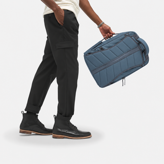 NOMATIC Backpack in Slate, carried by top handle in briefcase mode, side view