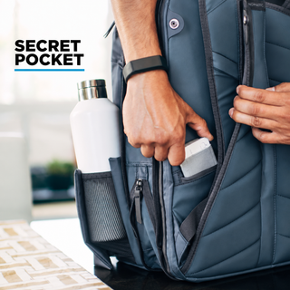 NOMATIC bag secret pocket, close-up of hand retrieving a phone next to a water bottle